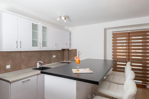 a kitchen with white cabinets and a black counter top at Hotel Agape in Zlatibor