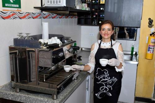 una mujer parada en una cocina sosteniendo dos tazas en Hotel Aroma del Bosque Posada Cafe en Tunja