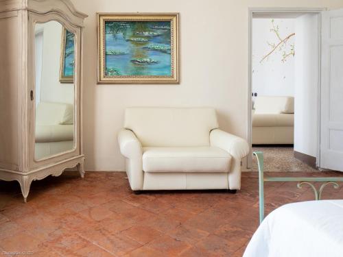 a living room with a chair and a mirror at Hotel Villa Costanza in Pontenure
