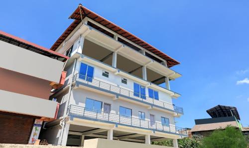 a tall white building with a balcony at Treebo Trend Doha King in Madikeri