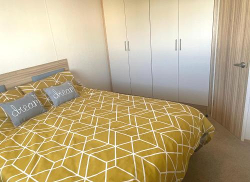 a bedroom with a yellow and white bed with two pillows at The Hudson @ Silversands in Lossiemouth