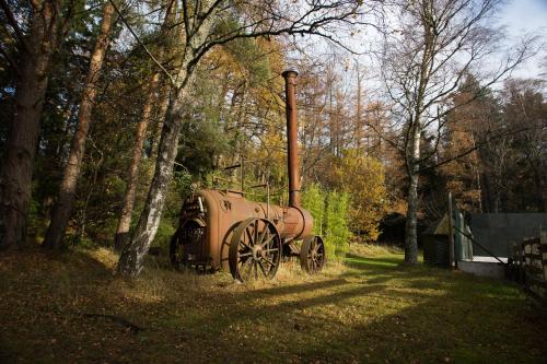 an old truck is sitting in the grass near trees at The Bungalow in Elgin