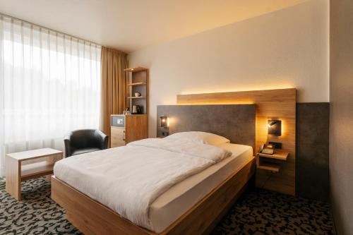 a bedroom with a bed and a desk and a chair at Caravelle Hotel im Park in Bad Kreuznach