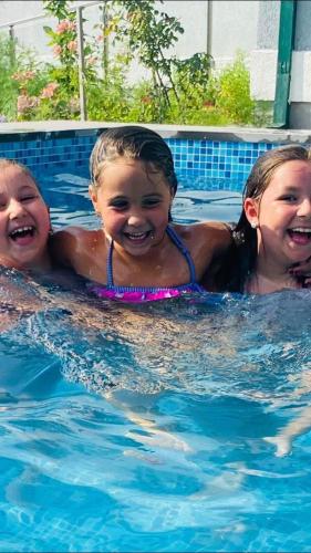 three children are smiling in a swimming pool at Guest House Botanical Paradise in Mtsvane Kontskhi