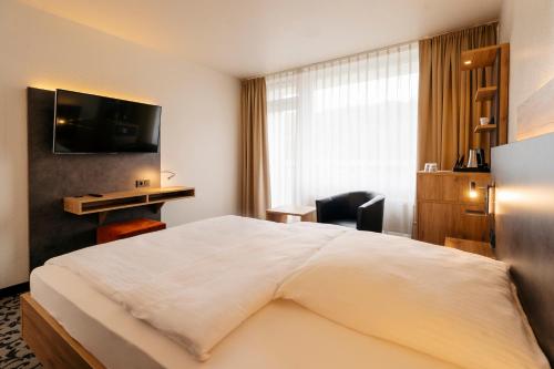 a hotel room with a large bed and a desk at Caravelle Hotel im Park in Bad Kreuznach