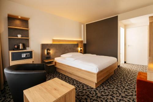 a hotel room with a bed and a chair at Caravelle Hotel im Park in Bad Kreuznach