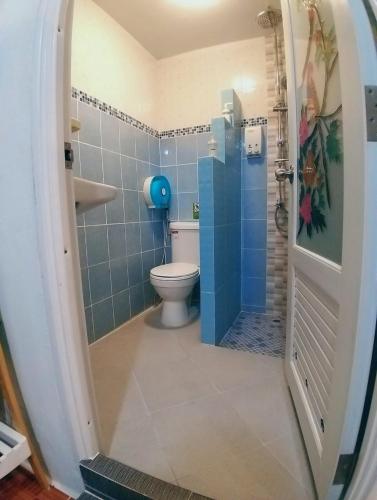 a bathroom with a toilet and a blue tiled wall at Acozyposhtel in Bangkok