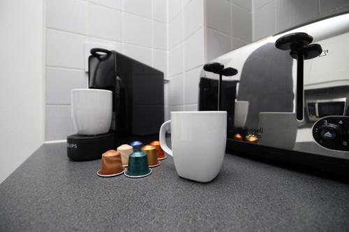 a kitchen counter with two cups and a coffee maker at TRUSCOTT - Spacious Home, High Speed Wi-Fi, Free Parking, Garden, Table Football in Swindon