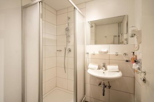 a bathroom with a shower, sink, and mirror at Caravelle Hotel im Park in Bad Kreuznach