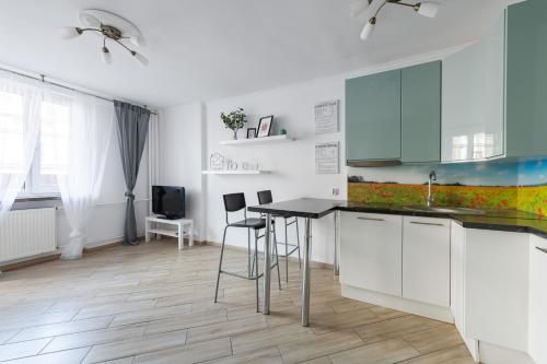 ワルシャワにあるMokotowska 67 Prywatne mieszkanie z balkonem w Centrum miasta i w pobliżu Ambasady USAの白いキャビネット、テーブルと椅子付きのキッチンが備わります。