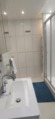 La salle de bains blanche est pourvue d'un lavabo et d'une douche. dans l'établissement Comfortable Room With Ensuite, à Londres