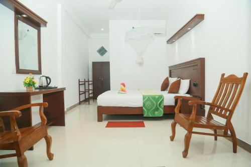 1 dormitorio con 1 cama y 2 mecedoras en Suwa Arana Resort en Mirissa