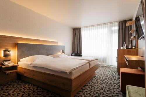 a hotel room with a large bed and a window at Caravelle Hotel im Park in Bad Kreuznach