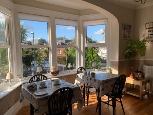 ein Esszimmer mit einem Tisch, Stühlen und Fenstern in der Unterkunft San Brelade in Paignton