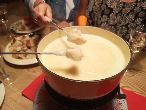 a person cooking food in a pot on a table at Maison Le ROZET in Les Gras