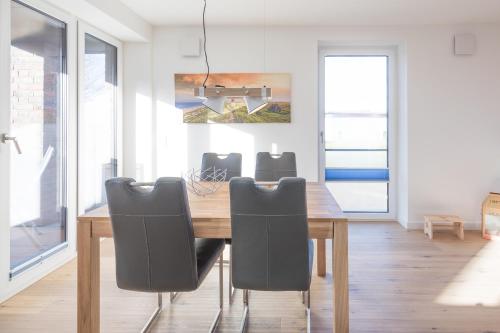 a dining room with a wooden table and chairs at Verpuusten in Husum