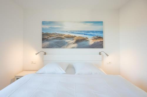 a bedroom with a white bed and a painting on the wall at Verpuusten in Husum