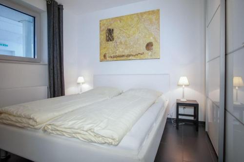 - un lit blanc dans une chambre ornée d'une peinture murale dans l'établissement Haus-Zur-Mole-Wohnung-8-Leonardo, à Großenbrode