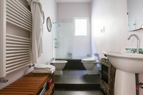 LOVELY MILANO - Beautiful loft with terrace in Porta Romana في ميلانو: حمام مع دورتين مياه وحوض استحمام ومغسلة