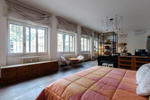LOVELY MILANO - Beautiful loft with terrace in Porta Romana في ميلانو: غرفة نوم بسرير كبير ومكتب ونوافذ
