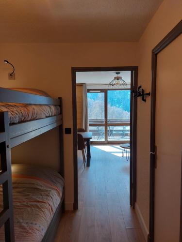 1 Schlafzimmer mit 2 Etagenbetten und einer Tür, die auf eine Terrasse führt in der Unterkunft Studio Le Flocon entièrement rénové in Les Orres