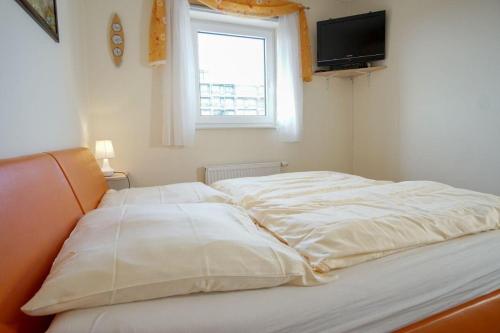 un letto con lenzuola bianche, una finestra e una TV di Haus-Ostseeapartments-am-Fehmarnsund-Wohnung-26-Wellenrauschen a Grossenbrode