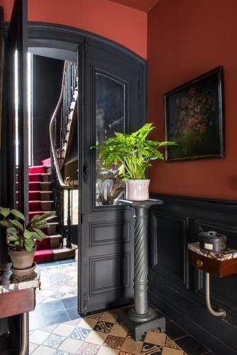 un pasillo con una puerta negra con macetas en La Villa Augustine en Dieppe