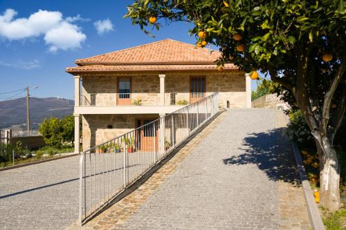 a house with an orange tree in front of a fence at Casa das Eiras 