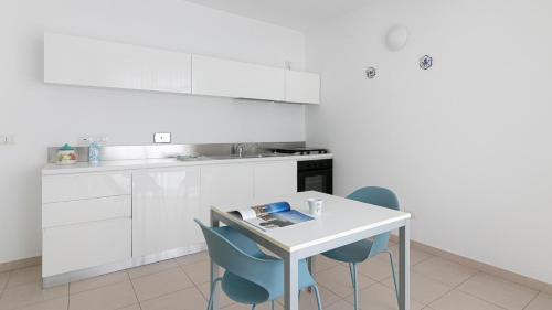 a white kitchen with white cabinets and blue chairs at Residenza Excelsior in Vasto
