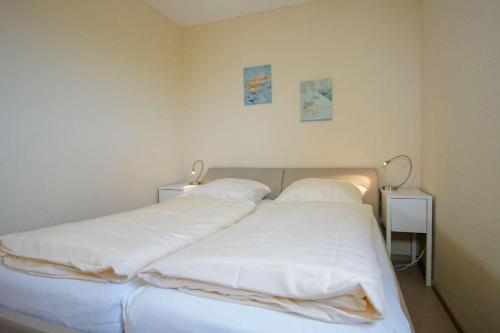 een slaapkamer met een bed met witte lakens en kussens bij Vier-Jahreszeiten-Haus-II-Wohnung-71-Meerbrise in Großenbrode