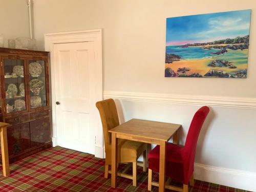 a table and chairs in a room with a painting on the wall at Southbank Guesthouse in Elgin