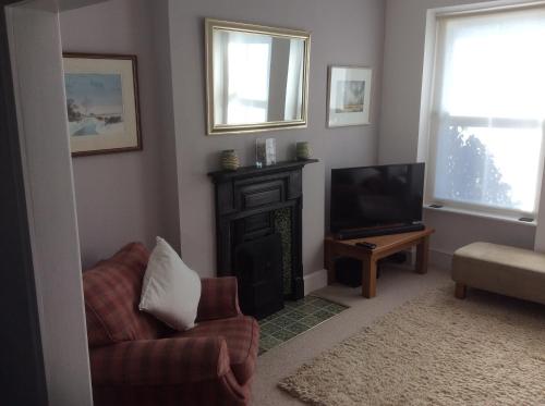 a living room with a fireplace and a chair and a television at Lovely Victorian town house close to the sea. in Bangor