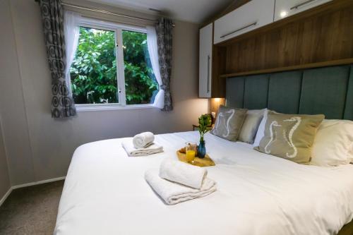 a bedroom with a large white bed with towels and a window at Sea Squirrel - Norfolk Cottage Agency in Holt