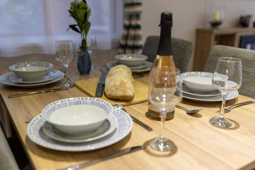 a wooden table with plates and glasses and a bottle of wine at Sea Squirrel - Norfolk Cottage Agency in Holt