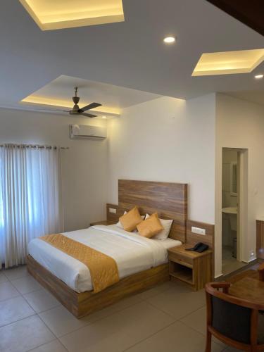 Munnar Ice Queen Resorts في مونار: غرفة نوم بسرير كبير وطاولة