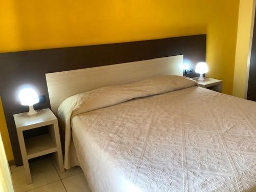 a bedroom with a white bed and two night stands at Hotel La Querceta in Montecatini Terme