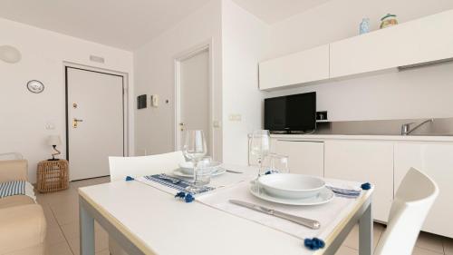a white kitchen with a table with plates and glasses on it at Residenza Excelsior in Vasto