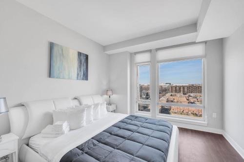 a white bedroom with a bed and a large window at Capitol Hill Fully Furnished Apartments in Washington, D.C.