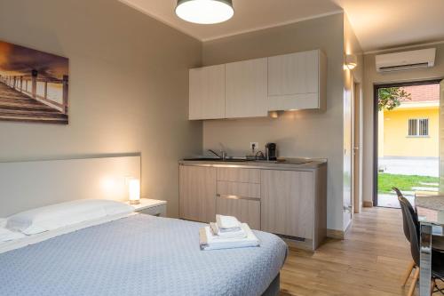 a bedroom with a bed and a table and a kitchen at Residence Le Palme in Torrazza Piemonte