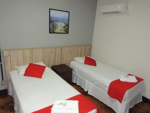 2 camas en una habitación con sábanas rojas y blancas en Hotel Gontijo Belo Horizonte - Próximo a Rodoviária e Praça Sete, en Belo Horizonte