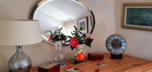 a table with a mirror and a vase with flowers on it at Tracebridge Cottage B&B in Stawley