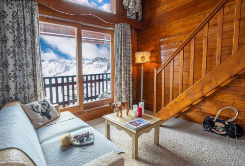a room with a couch and a window with a mountain view at Hôtel les Campanules by Les Etincelles in Tignes