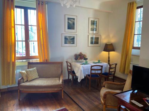 un salon avec une table, des chaises et des fenêtres dans l'établissement Très bel appartement dijonnais place Wilson GUTEMBERT, à Dijon