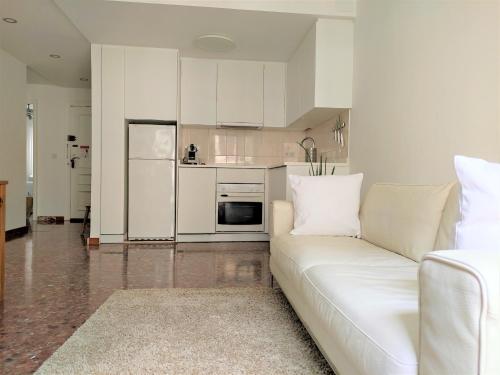 sala de estar con sofá blanco y cocina en ALOHALACANT Piso nuevo en la Playa y en el Ayuntamiento, en Alicante