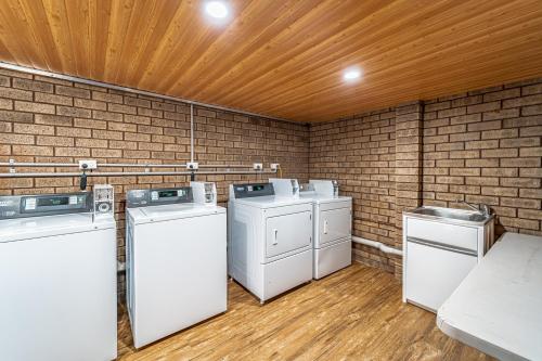eine Waschküche mit vier Waschgelegenheiten und einer Ziegelwand in der Unterkunft Carnarvon Motel in Carnarvon