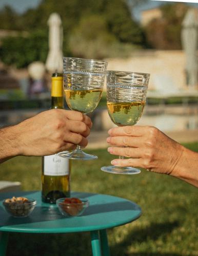 two people holding up glasses of wine on a table at Finca Gomera - Agroturismo Hotel in Cala Pi