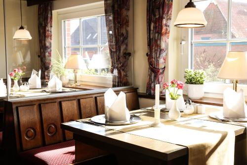 a dining room with a table and two windows at Hotel Zur Linde in Neddenaverbergen