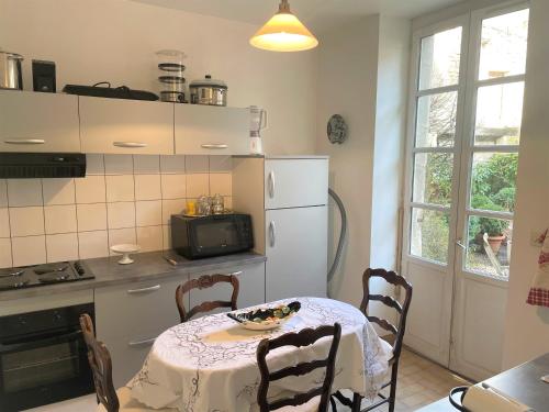 une cuisine avec une table et un réfrigérateur blanc dans l'établissement Sublime appartement Volendame, à Dijon