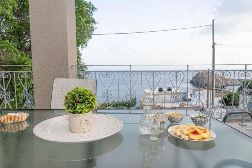 a glass table with a plate of food on a balcony at Tzortzi's Family Apartments in Kaloi Limenes