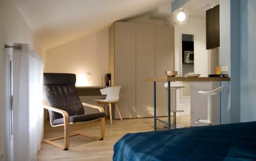 a bedroom with a chair and a table and a kitchen at Hotel Oliva in Aviano